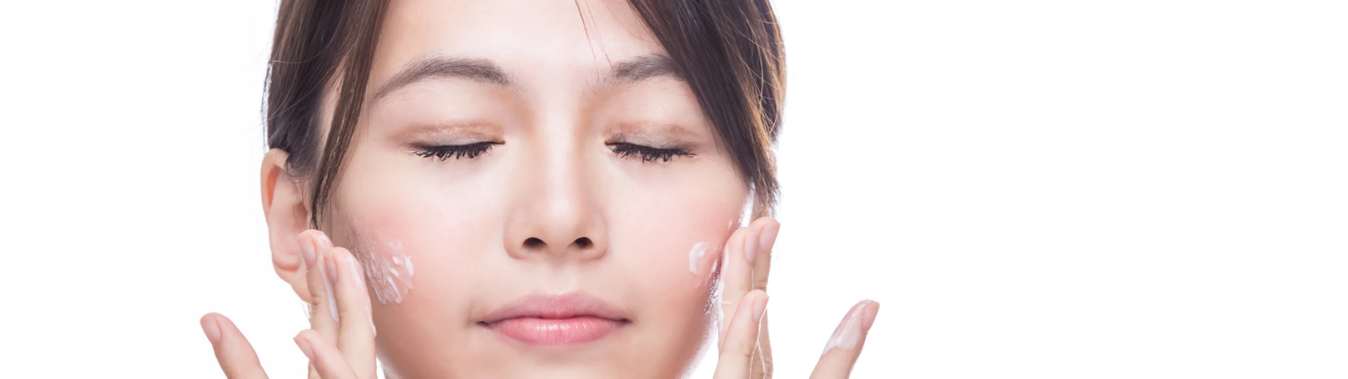 East Asian woman applying skincare to her face